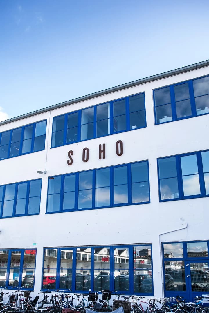 The SOHO building at Flæsketorvet, white with blue window frames, bicycles parked along its front.